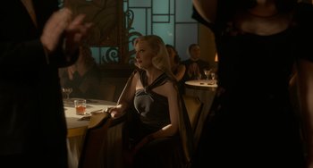Movie still from “Nightmare Alley” (2021), directed by Guillermo del Toro – A woman sitting at a table in front of a glass of wine; Medium shot, Over the shoulder angle