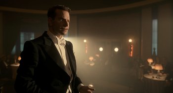Movie still from “Nightmare Alley” (2021), directed by Guillermo del Toro – A man in a tuxedo standing in a dimly - lit room; Medium shot, Low angle