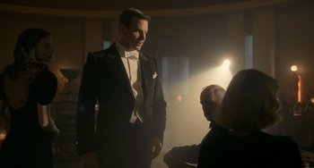 Movie still from “Nightmare Alley” (2021), directed by Guillermo del Toro – A man in a tuxedo standing next to another man in a suit; Medium shot, Over the shoulder angle
