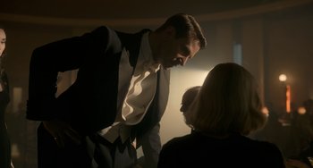 Movie still from “Nightmare Alley” (2021), directed by Guillermo del Toro – A man in a suit talking to a woman in a black suit; Medium shot, Over the shoulder angle