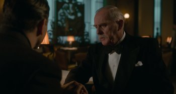 Movie still from “Nightmare Alley” (2021), directed by Guillermo del Toro – A man in a tuxedo shaking hands with another man in a suit; Medium shot, Over the shoulder angle