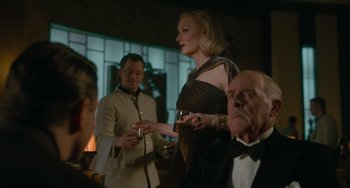 Movie still from “Nightmare Alley” (2021), directed by Guillermo del Toro – A woman standing in front of a group of people; Medium shot, Over the shoulder angle