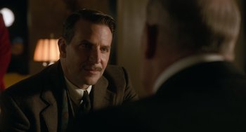 Movie still from “Nightmare Alley” (2021), directed by Guillermo del Toro – A man wearing a suit and tie talking to another man wearing a suit and tie; Close Up shot, Over the shoulder angle