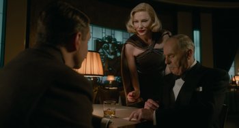 Movie still from “Nightmare Alley” (2021), directed by Guillermo del Toro – Two men and a woman sitting at a dinner table; Medium shot, Over the shoulder angle