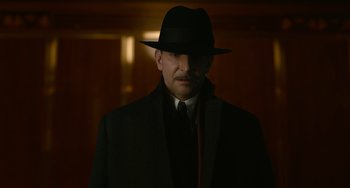 Movie still from “Nightmare Alley” (2021), directed by Guillermo del Toro – A man wearing a black hat and a black coat; Close Up shot, Low angle