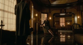 Movie still from “Nightmare Alley” (2021), directed by Guillermo del Toro – A woman sitting on a chair in a room with a man; Wide shot, Low angle