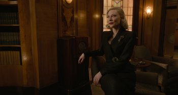 Movie still from “Nightmare Alley” (2021), directed by Guillermo del Toro – A woman sitting in front of an old fashioned radio; Medium shot, Low angle