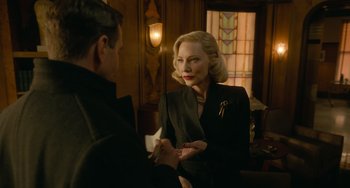 Movie still from “Nightmare Alley” (2021), directed by Guillermo del Toro – An older woman in a black suit talking to a younger man; Medium shot, Over the shoulder angle