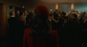 Movie still from “Nightmare Alley” (2021), directed by Guillermo del Toro – A woman in a red dress and a red hat; Medium shot, Over the shoulder angle