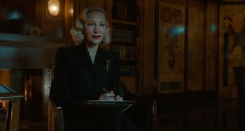 Movie still from “Nightmare Alley” (2021), directed by Guillermo del Toro – A woman sitting in a chair writing on a piece of paper; Medium shot, Over the shoulder angle