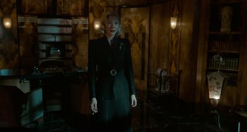 Movie still from “Nightmare Alley” (2021), directed by Guillermo del Toro – A woman in a black suit standing in front of a mirror; Medium shot, Low angle