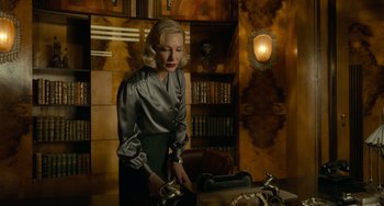 Movie still from “Nightmare Alley” (2021), directed by Guillermo del Toro – A woman standing in front of a table with a tea pot on top of it; Medium shot, Low angle