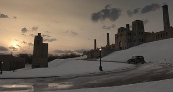 Movie still from “Nightmare Alley” (2021), directed by Guillermo del Toro – A street light on the side of a road near some buildings; Extreme Wide shot, Low angle