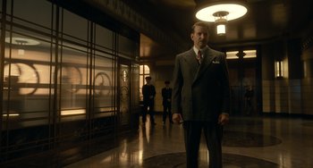 Movie still from “Nightmare Alley” (2021), directed by Guillermo del Toro – A man in a suit and tie in a lobby; Wide shot, Low angle