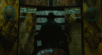 Movie still from “Nightmare Alley” (2021), directed by Guillermo del Toro – A man wearing a hat is standing on the escalator; Medium shot, Low angle