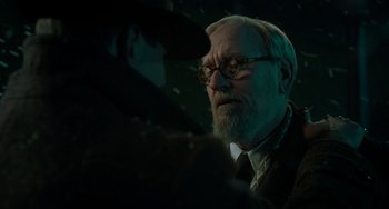 Movie still from “Nightmare Alley” (2021), directed by Guillermo del Toro – An older man wearing a suit and tie; Close Up shot, Over the shoulder angle