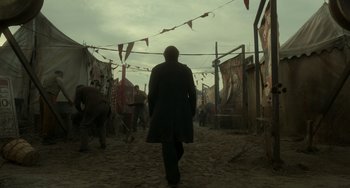 Movie still from “Nightmare Alley” (2021), directed by Guillermo del Toro – A man walking down a dirt path in a field; Wide shot, Low angle