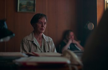 Movie still from “Nitram” (2021), directed by Justin Kurzel – A woman sitting in front of a table with another woman; Medium shot, Over the shoulder angle