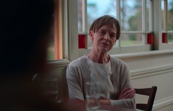 Movie still from “Nitram” (2021), directed by Justin Kurzel – An older woman sitting in front of a glass of water; Close Up shot, Over the shoulder angle
