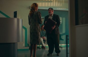 Movie still from “Nitram” (2021), directed by Justin Kurzel – A man and a woman standing next to each other in a room; Medium shot, Over the shoulder angle