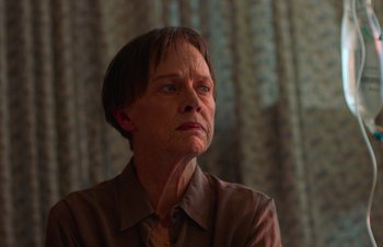 Movie still from “Nitram” (2021), directed by Justin Kurzel – An older woman with short brown hair wearing a brown shirt; Close Up shot, Low angle