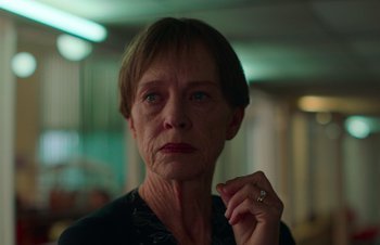 Movie still from “Nitram” (2021), directed by Justin Kurzel – An older woman is looking at the camera; Close Up shot, Over the shoulder angle