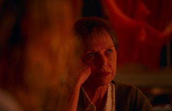Movie still from “Nitram” (2021), directed by Justin Kurzel – An older woman sitting in front of a window; Close Up shot, Over the shoulder angle