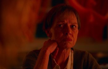 Movie still from “Nitram” (2021), directed by Justin Kurzel – An older woman sitting in front of a window; Close Up shot, Over the shoulder angle