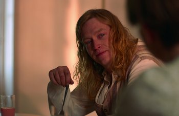 Movie still from “Nitram” (2021), directed by Justin Kurzel – A man with long red hair is holding something; Close Up shot, Over the shoulder angle