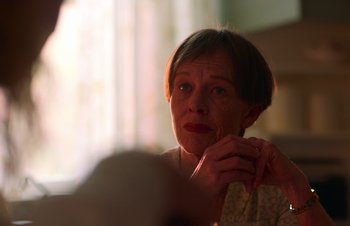 Movie still from “Nitram” (2021), directed by Justin Kurzel – An older woman is looking at the camera; Close Up shot, Over the shoulder angle