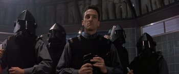 Movie still from “No Escape” (1994), directed by Martin Campbell – A group of men standing next to each other holding guns; Close Up shot, Low angle