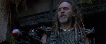 Movie still from “No Escape” (1994), directed by Martin Campbell – A person with a beard; Close Up shot, Low angle