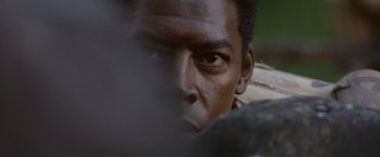 Movie still from “No Escape” (1994), directed by Martin Campbell – A man's face as he looks into the camera; Extreme Close Up shot, Low angle