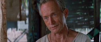 Movie still from “No Escape” (1994), directed by Martin Campbell – A person wearing a necklace; Close Up shot, Low angle