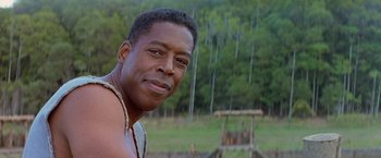 Movie still from “No Escape” (1994), directed by Martin Campbell – A person with a tree in the background; Close Up shot, Over the shoulder angle