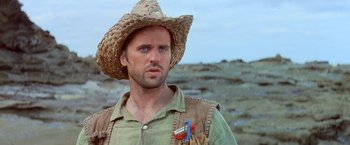 Movie still from “No Escape” (1994), directed by Martin Campbell – A person wearing a straw hat; Close Up shot, Low angle