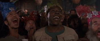 Movie still from “No Escape” (1994), directed by Martin Campbell – A group of people in a room wearing hats and smiling; Close Up shot, Low angle