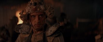 Movie still from “No Escape” (1994), directed by Martin Campbell – A person wearing a helmet; Close Up shot, Low angle