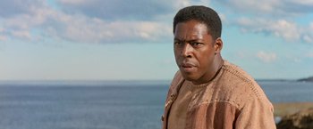 Movie still from “No Escape” (1994), directed by Martin Campbell – A person near a body of water; Close Up shot, Low angle