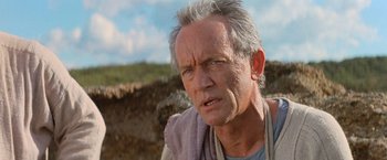 Movie still from “No Escape” (1994), directed by Martin Campbell – An older man with grey hair looking at the camera; Close Up shot, Low angle