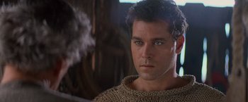 Movie still from “No Escape” (1994), directed by Martin Campbell – A person wearing a sweater and looking at the camera; Close Up shot, Over the shoulder angle