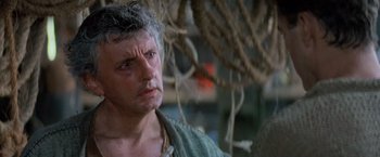 Movie still from “No Escape” (1994), directed by Martin Campbell – A person wearing a shirt; Close Up shot, Low angle