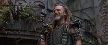 Movie still from “No Escape” (1994), directed by Martin Campbell – A man with dreadlocks and a beard is smiling; Close Up shot, Low angle