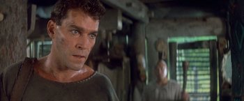 Movie still from “No Escape” (1994), directed by Martin Campbell – A person wearing a sweater; Close Up shot, Low angle