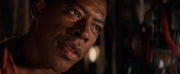 Movie still from “No Escape” (1994), directed by Martin Campbell – A person's face in a dark room; Close Up shot, Low angle