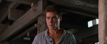 Movie still from “No Escape” (1994), directed by Martin Campbell – A person wearing a blue shirt; Close Up shot, Low angle