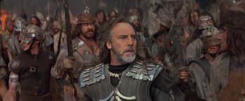 Movie still from “No Escape” (1994), directed by Martin Campbell – A group of men in costume in the middle of a scene; Close Up shot, Low angle