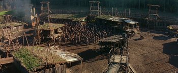 Movie still from “No Escape” (1994), directed by Martin Campbell – An aerial view of a group of people standing in a field; Extreme Wide shot, High angle