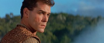 Movie still from “No Escape” (1994), directed by Martin Campbell – A man's face in front of trees; Close Up shot, Low angle