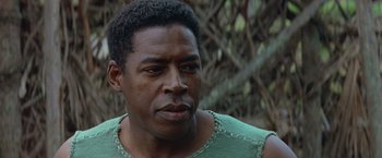Movie still from “No Escape” (1994), directed by Martin Campbell – A person wearing a green tank top; Close Up shot, Low angle